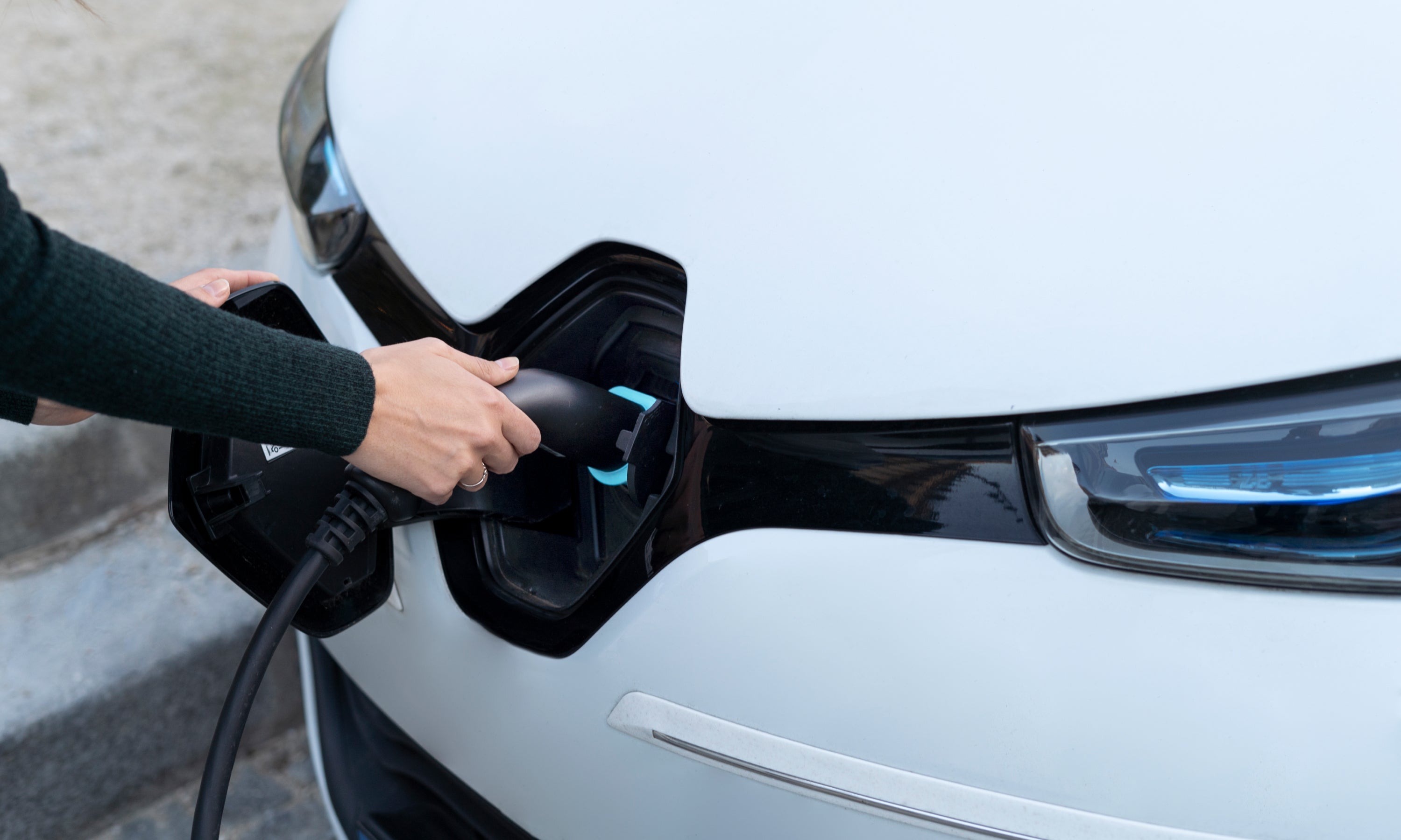 Stecken sie das elektroauto-ladegerät per hand in das elektroauto, um die  batterie aufzuladen, und überprüfen sie gleichzeitig die  batteriestatusanzeige auf dem smartphone. zukünftige nachhaltige und  saubere energie für elektroautos